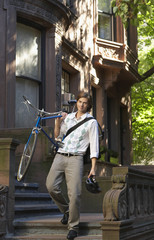 Full length of young businessman carrying bicycle while descending steps