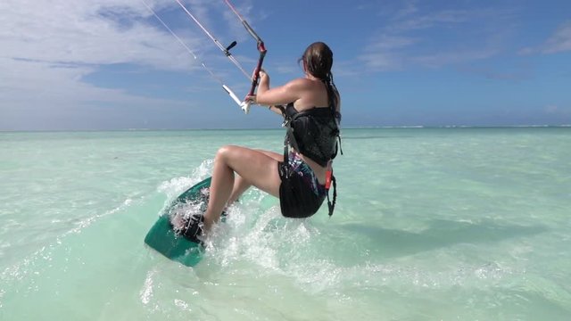 SLOW MOTION CLOSEUP: Surfer female doing kiting water start and kite surfs away