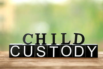 Text CHILD CUSTODY made of black blocks and letters on table against blurred background, closeup