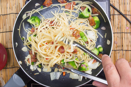 Chef stir fried Spaghetti with tongs