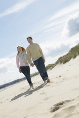 Full length of loving couple walking on sandy beach