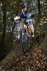 Young man riding mountain bike through forest