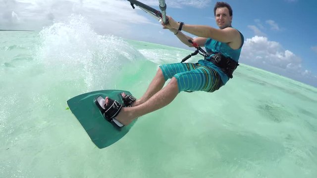 CLOSE UP: Cheerful young kiter sportsman kiteboarding on perfect turquoise sea