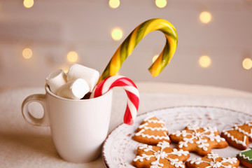 Beautiful Christmas background with gingerbread cookies on white plate with Cup of marshmallows and candy