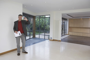 Full length of a male real estate agent photographing new property
