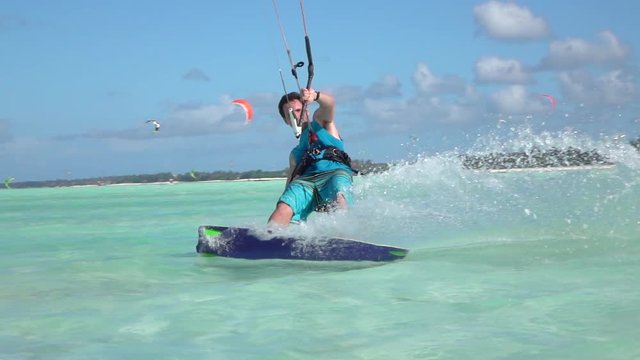 SLOW MOTION: Happy smiling surfer guy kiteboarding in perfect tropical lagoon