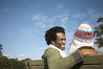 Happy young man looking at woman while sitting on park bench