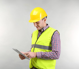 Fototapeta premium Handsome warehouse worker with tablet computer on light background