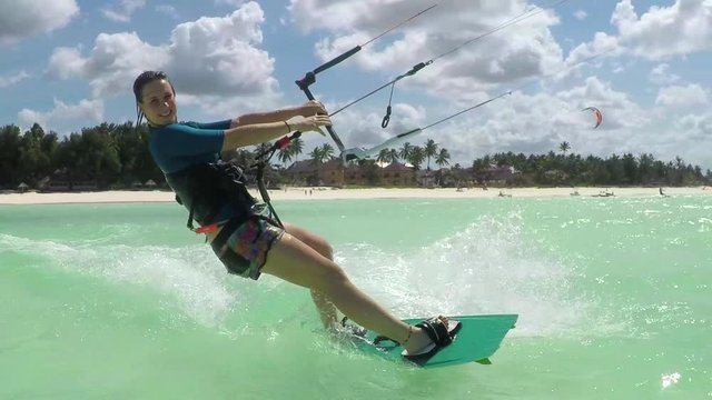 SLOW MOTION: Happy young surfer woman kiteboarding in beautiful blue lagoon