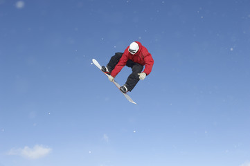 Full length of snowboard free rider making high jump against blue sky