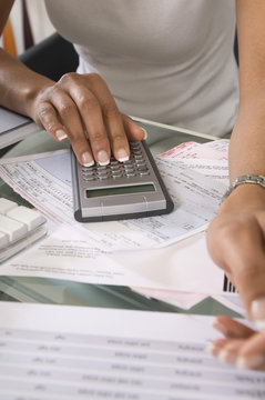Midsection of a woman calculating budget at home