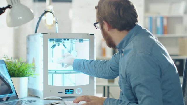 Young Bearded Engineer Expects 3D Model that He Just Created in His 3D Printer. He Sits at His Desk in Modern Office.  Shot on RED Cinema Camera in 4K (UHD).