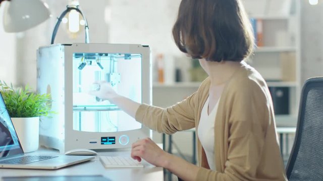 Young Woman Engineer Expects 3D Printed Detal that She Just Made with Her 3D Printer.  Shot on RED Cinema Camera in 4K (UHD).