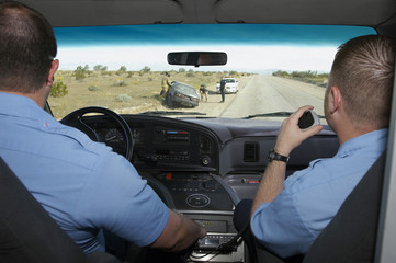 Paramedics looking through windshield at car crash scene