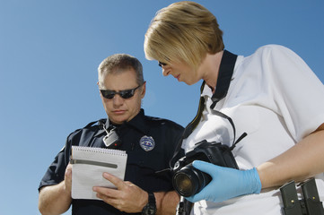 Low angle view of police officer and investigator with camera