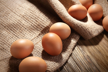 Raw eggs on sackcloth on wooden table
