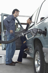Couple talking in van with fuel pump refueling it