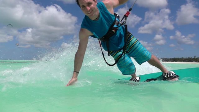 SLOW MOTION: Cheerful smiling kite surfer hand drag kitesurfing in tropical sea
