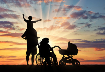 Fototapeta na wymiar Disabled person in wheelchair and pram and family sunset