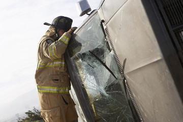 Side view of a firefighter inspecting a crashed car