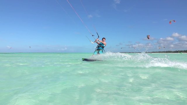 SLOW MOTION: Happy smiling surfer has fun kiteboarding in blue tropical lagoon
