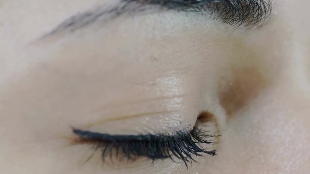 young woman opens her eye: closeup portrait of woman's brown eye