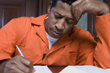 An African American male criminal writing on paper in courtroom