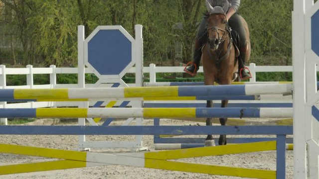 SLOW MOTION: Unrecognizable rider and horse jumping difficult showjumping course