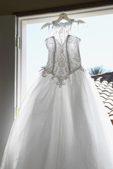 Fototapeta na wymiar Beautiful bridal dress hanging by window