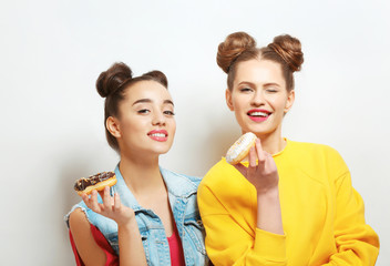 Funny young women with tasty donuts on white background