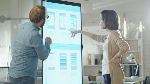 Young Coworkers Discuss Charts Drawn on Their Electronic Whiteboard. Their Office is developer and Modern Looking. Shot on RED Cinema Camera in 4K (UHD).