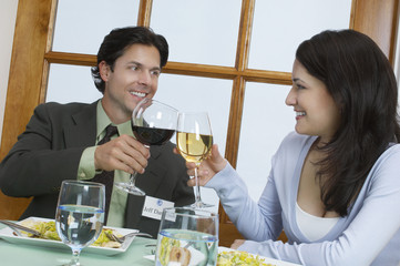 Young couple at restaurant table toasting wineglasses