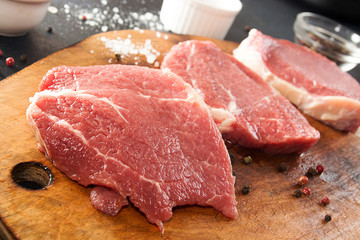 Cooking dinner. Overhead pieces raw pork steaks on chopping boar