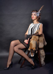 The beautiful woman in a suit in Chicago style sits on chair