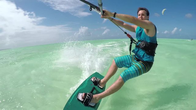 CLOSE UP: Young kiter on summer vacation kiteboarding on perfect turquoise sea