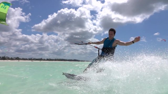 SLOW MOTION: Extreme kite surfer kiteboarding and splashing seawater into camera