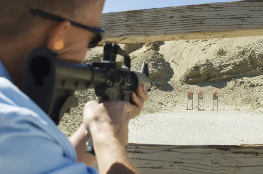 Closeup of a military man aiming machine gun at firing range during weapons training