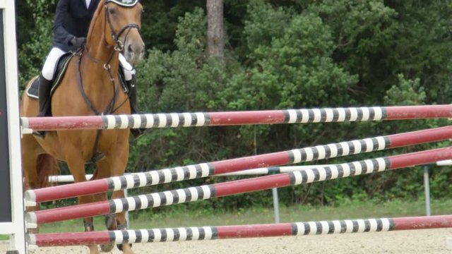 SLOW MOTION: Unrecognizable rider and horse jumping a fence in equestrian event