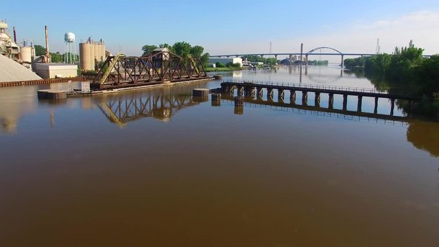 Scenic flight over still river, railroad bridge, train trestle.
