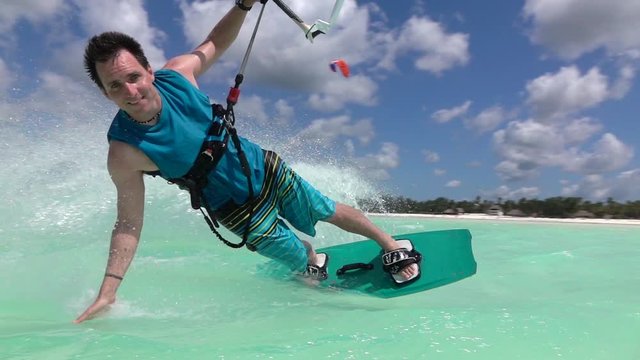 SLOW MOTION CLOSE UP: Happy smiling kite surfer kiteboarding in tropical lagoon