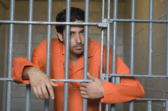 Portrait of prisoner standing behind prison bars