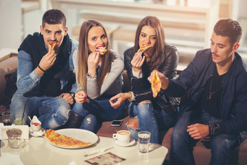 Young people in casual clothes eating pizza, talking