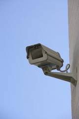 Closeup of a security camera mounted on wall against blue sky