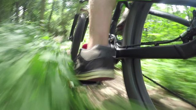 CLOSE UP: Unrecognizable man pedaling electric bike on offroad trail in forest