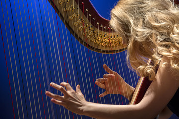 Closeup portrait of young girl playing the harp during concert at musical theater