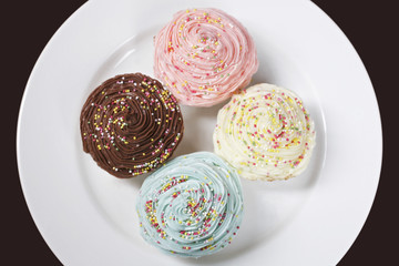 High angle view of colorful cupcakes on plate isolated over black background