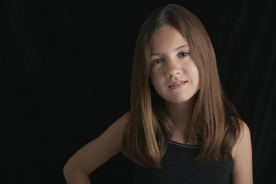 Portrait of young brunette girl against black background