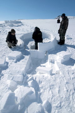 Inuit Cutting Snow Blocks Using A Saw And A Knife To Make An Igloo, Nunavut, Canada