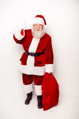 Smiling Santa in traditional costume with sack saying hello