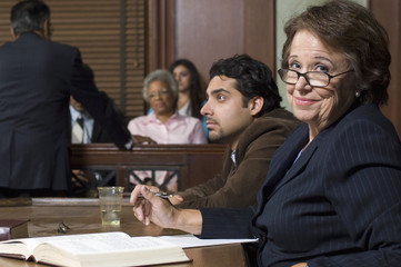 Portrait of a happy defense lawyer sitting with client in courthouse